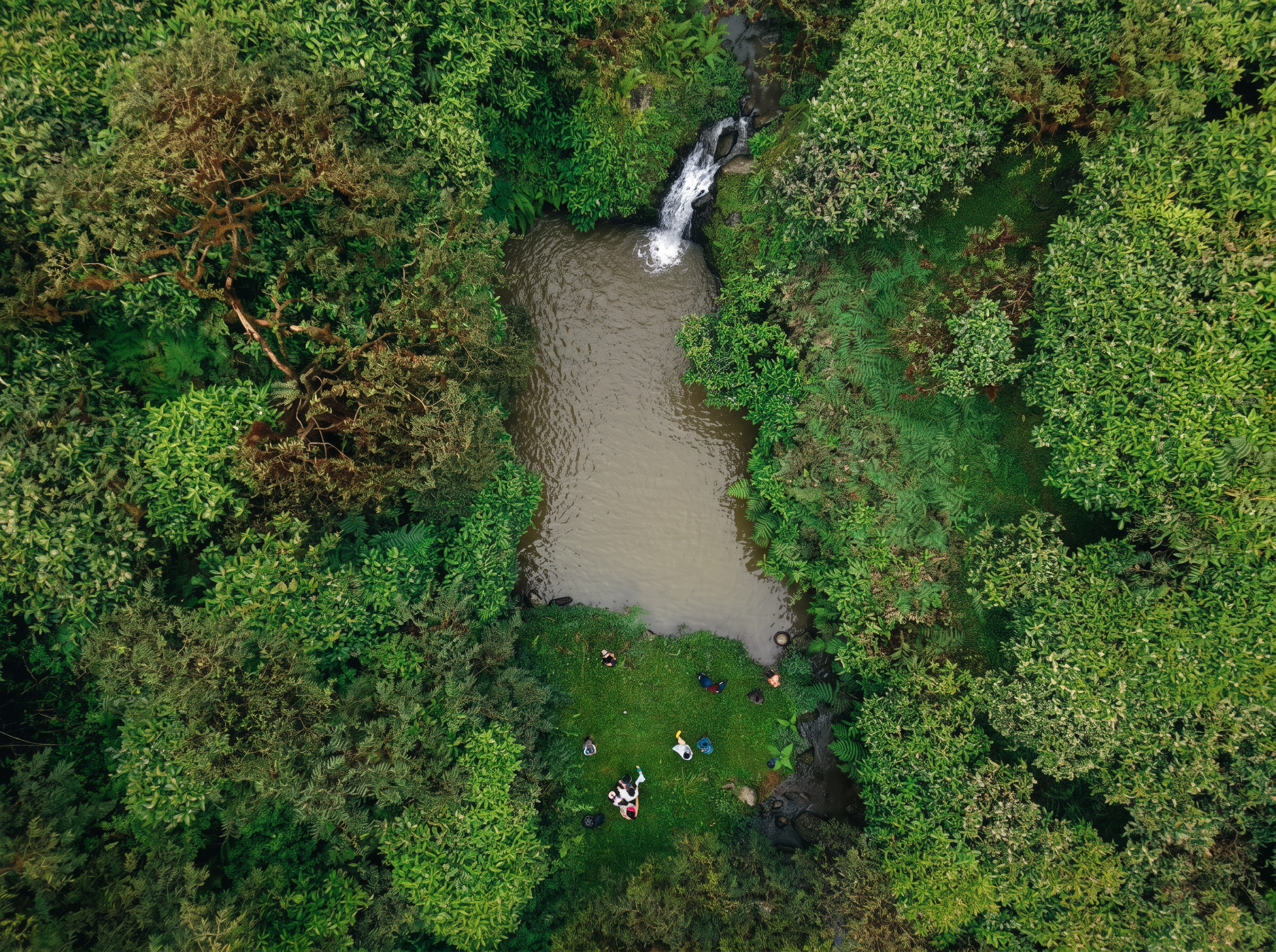 Aerial view of guests gathered by a highland waterfall pool