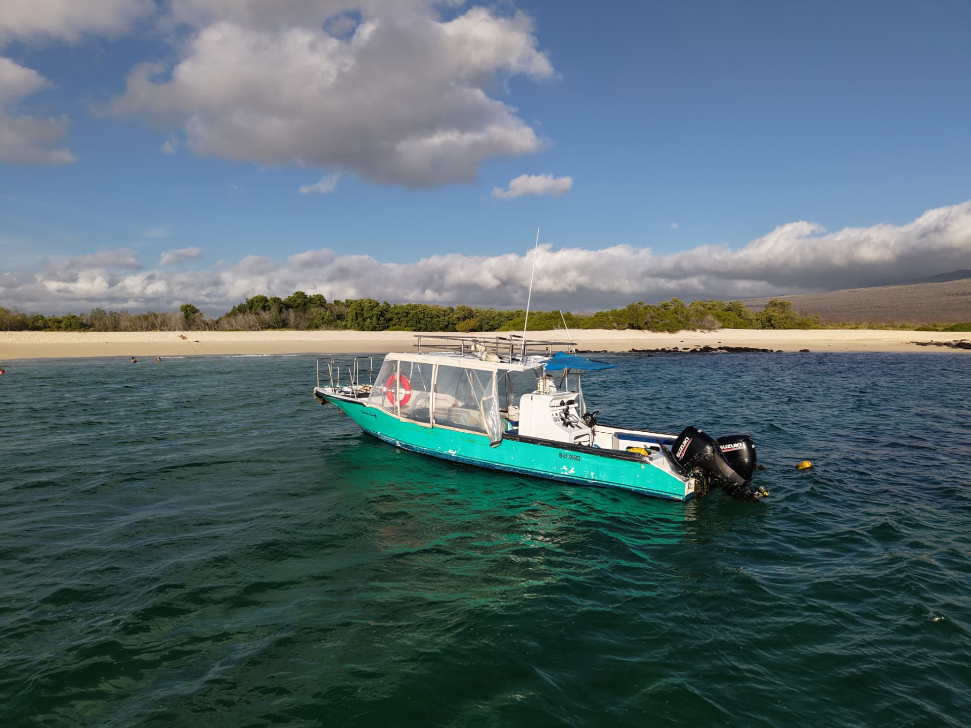 Turquoise support boat anchored beside a Galápagos beach