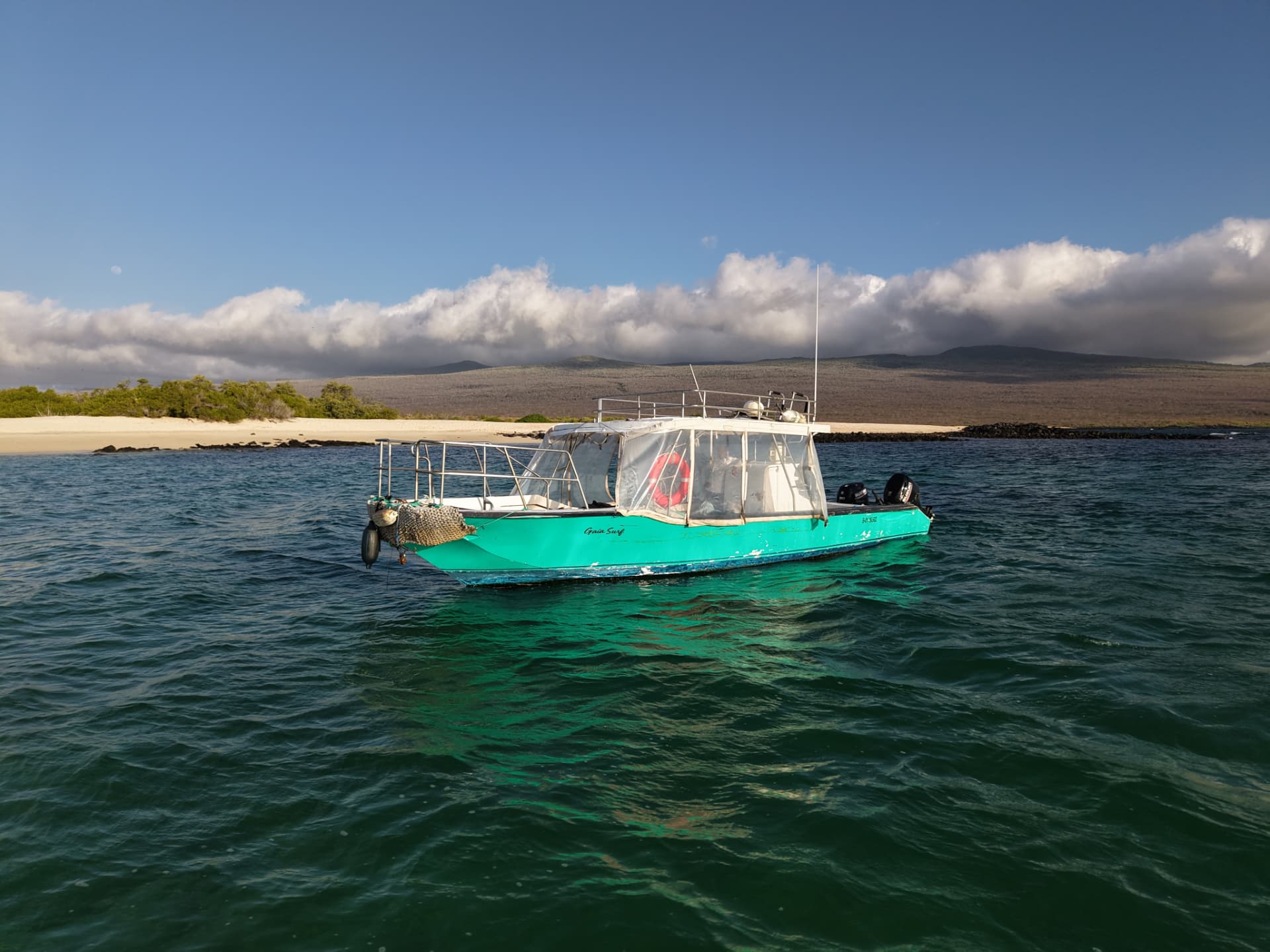 Gaia Surf support boat in a bay beneath the San Cristóbal highlands