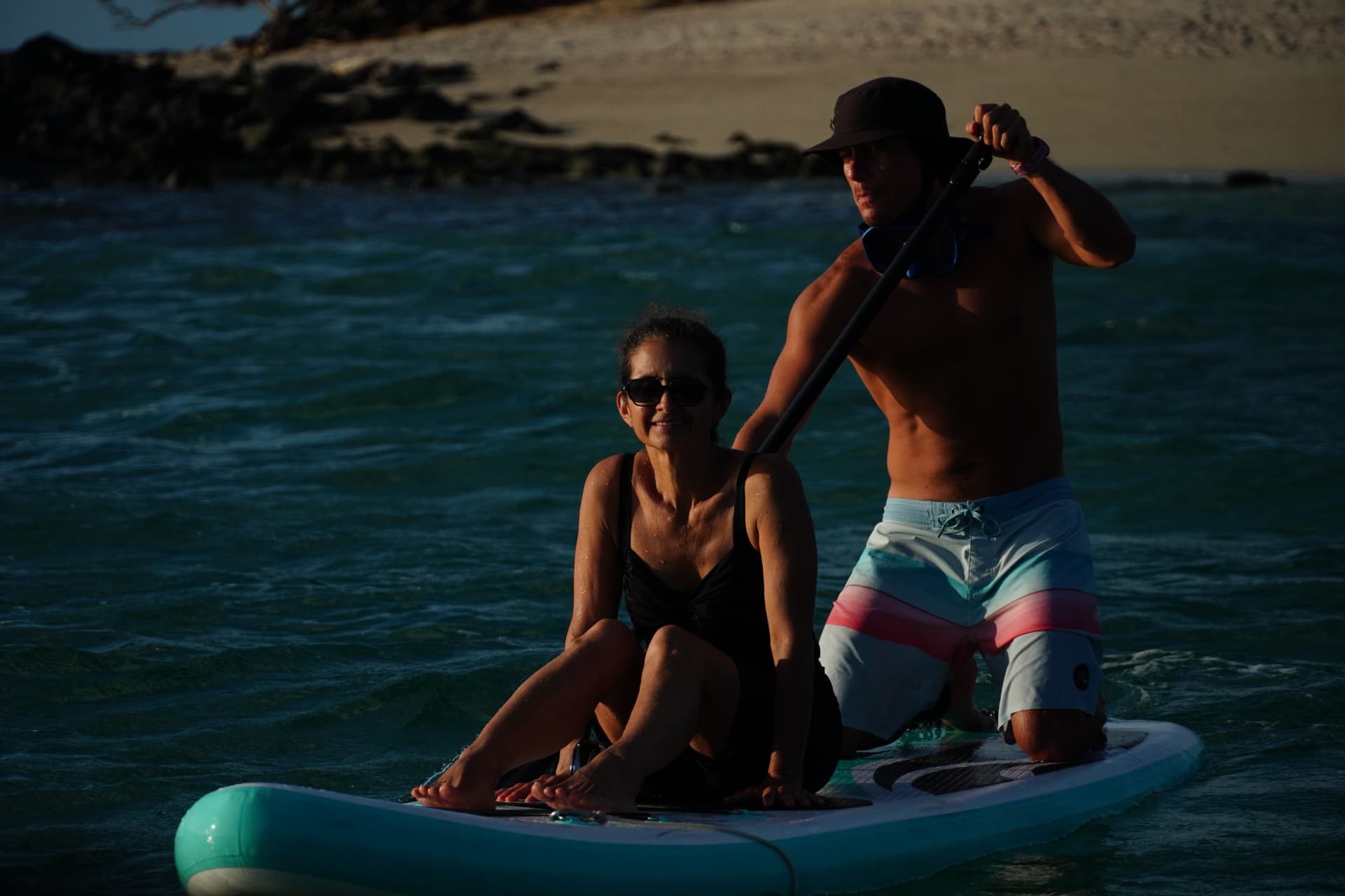 A couple sharing a paddleboard in the turquoise water off San Cristóbal
