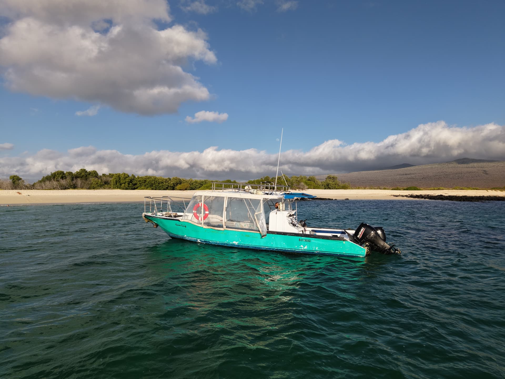 Side view of the Gaia Surf support boat on clear coastal water