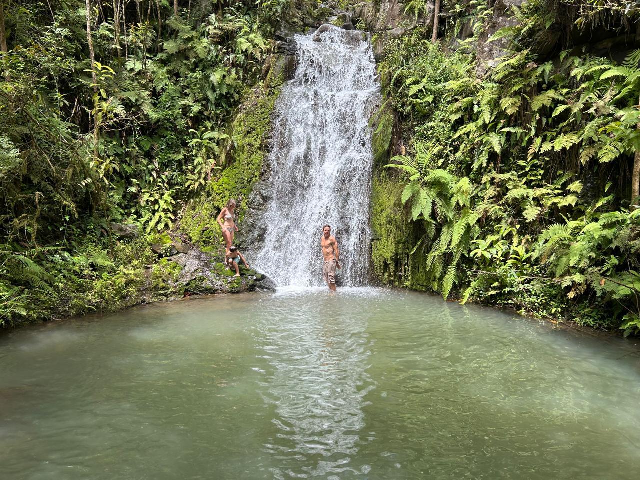Natural waterfall in the San Cristóbal highlands with visitors swimming