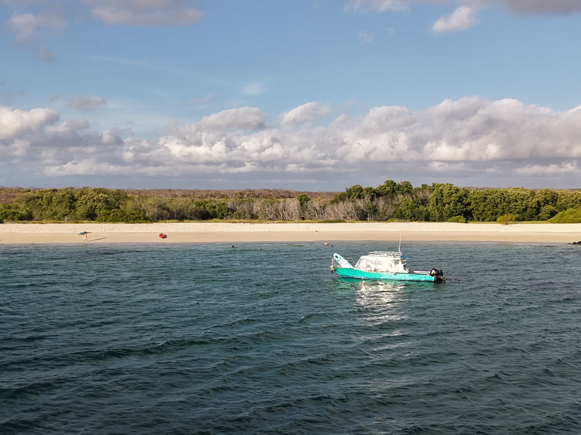 Gaia Surf support boat anchored off a white-sand Galápagos beach
