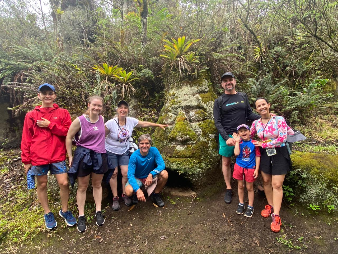 Visitors beside a mossy rock face in the Floreana highlands